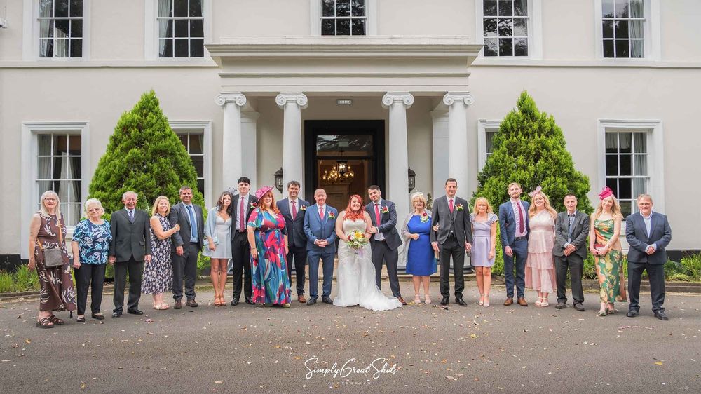 A bridal party pose in front of Eastwood Hall entrance, captured by a wedding photographer.
