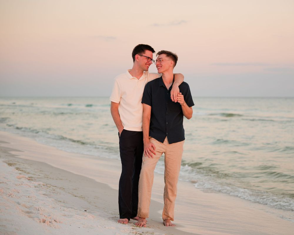 A couple walks hand in hand along a serene beach at sunset, creating romantic silhouettes against the ocean backdrop.