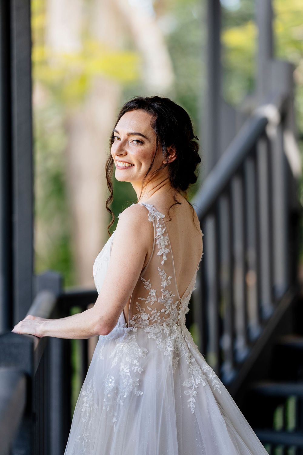 A bride in a delicate lace wedding gown poses gracefully on a porch in multiple candid shots.