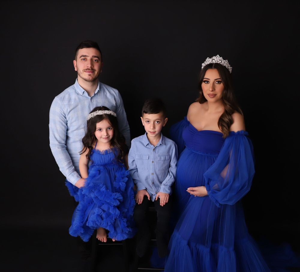 A family portrait with matching blue outfits against a black background.