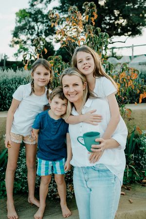 Family group posing together in garden with orange flowers in background.