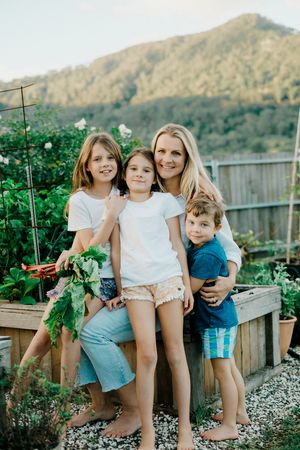 Family standing together in front of raised garden bed with mountain view.