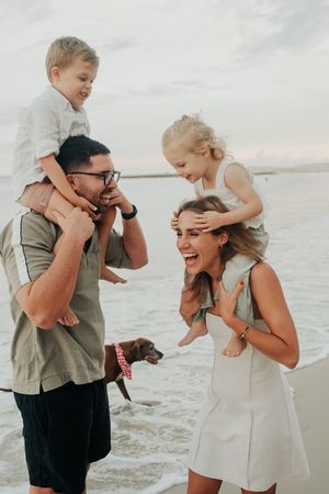 Playful family moments at the beach with children and laughter during sunset.