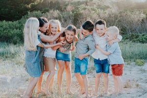 Children sitting together outdoors in casual summer clothing.