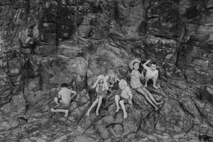 Group portrait of children sitting together on rocky terrain.