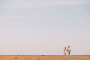 Distant figures walking along horizon line against pastel sky.
