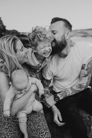 Candid black and white photo of a family laughing together while lying on the ground.
