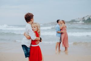 Playful beach scenes with family members in red and white clothing against ocean backdrop.