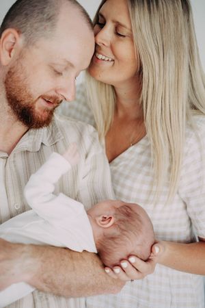 An intimate family moment captured in soft tones with a newborn baby.