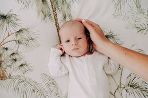 A gentle moment with a baby against a botanical wallpaper background.