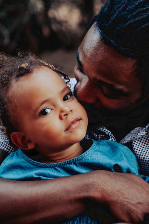 A tender moment between parent and child in dim lighting.