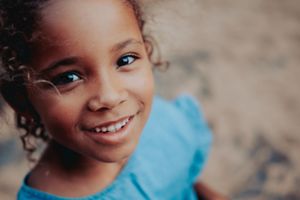 Close-up portrait of a child with curly hair and bright smile.