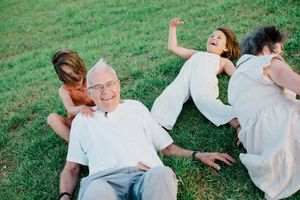A joyful group relaxes together on green grass during a sunny day outdoors.