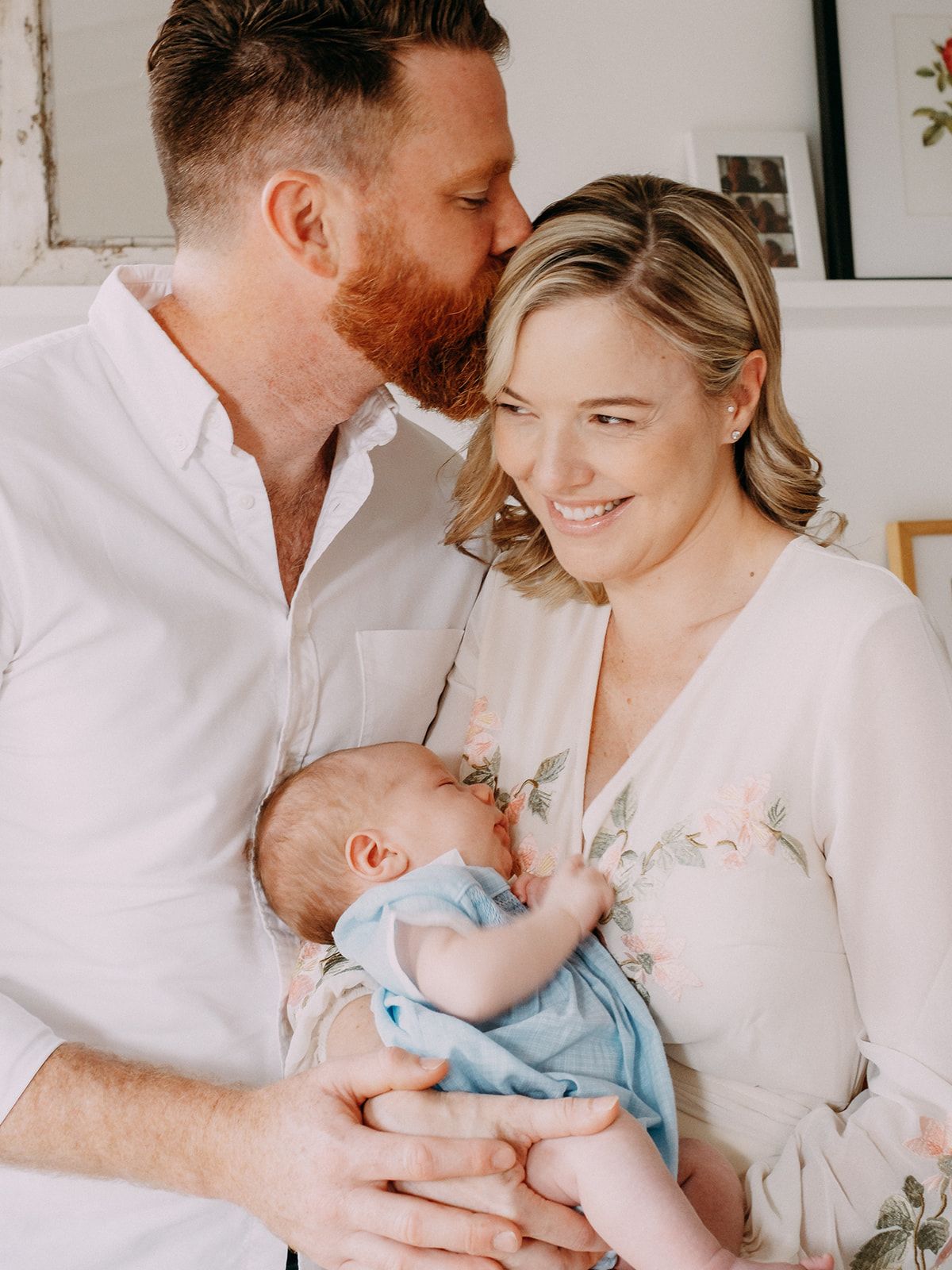 An intimate indoor family portrait with a newborn baby in soft natural light.