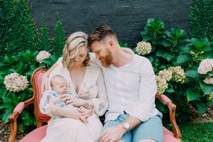 A tender family moment shared on a coral chair surrounded by blooming hydrangeas.