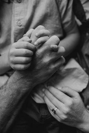 Close-up black and white photo of intertwined hands showing intimacy and connection.
