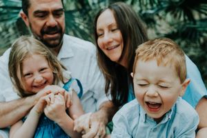 A candid family photo capturing genuine laughter and joy outdoors.