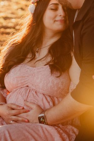 A romantic maternity portrait bathed in golden sunset light.