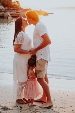 Family sharing intimate moments on beach during sunset photoshoot.