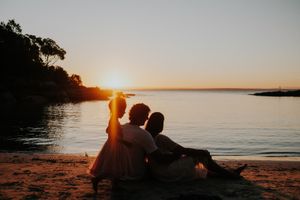 Silhouette of couple relaxing on beach during dramatic sunset.