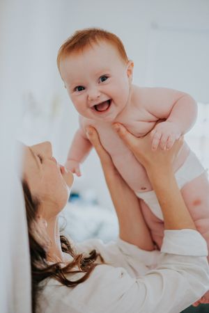 Joyful indoor playtime between parent and baby in white setting.