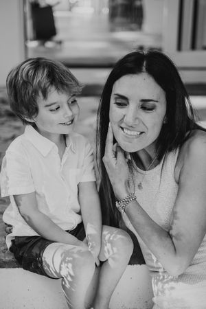 Black and white intimate portrait of tender family moment on white bedding.