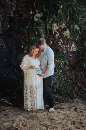A couple in a garden setting sharing an intimate moment while looking at something together.