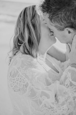 Intimate black and white close-up of couple in romantic moment wearing white lace.