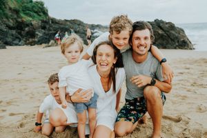 Family enjoying playful moments together on a sunny beach.