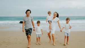 Family members walking together along a scenic beach with ocean waves in the background.