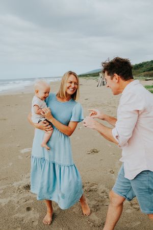 Family playing and laughing together during a casual beach photoshoot.