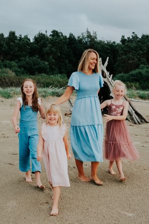 Group wearing coordinating pastel dresses walking together on a beach.