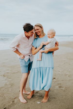 Family sharing tender moments together on a sandy beach at sunset.