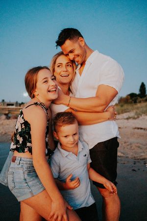 A family shares tender moments together during a beach photoshoot at golden hour.