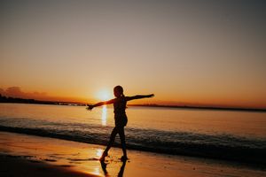 Silhouettes of people enjoying a dramatic orange sunset at the beach.
