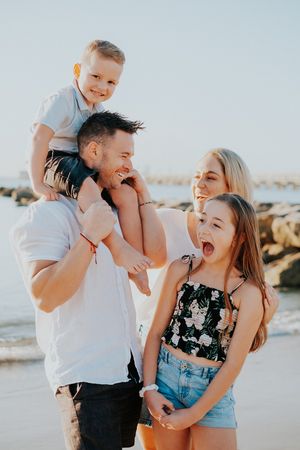 A joyful family shares laughs and embraces while playing together on a sunny beach.