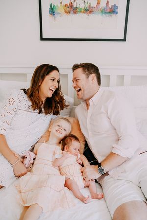 A family shares intimate moments and laughter while relaxing together on a white bed.