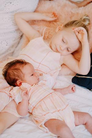 Candid moments of children in peach-colored outfits relaxing on white bedding.