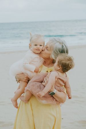 A tender beach scene with three generations sharing an affectionate moment in soft lighting.