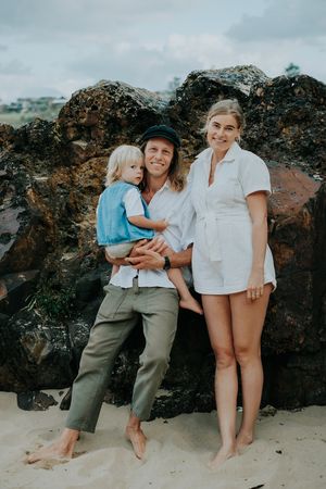 A casual family portrait against dramatic black rocks on a beach.