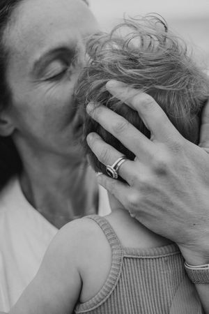 An intimate black and white close-up showing a tender moment between parent and child.