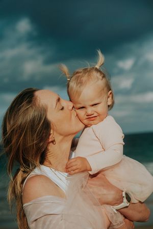 Mother and child share intimate moments against dramatic stormy sky backdrop.
