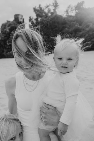 A candid black and white moment of a parent and child outdoors with windswept hair.