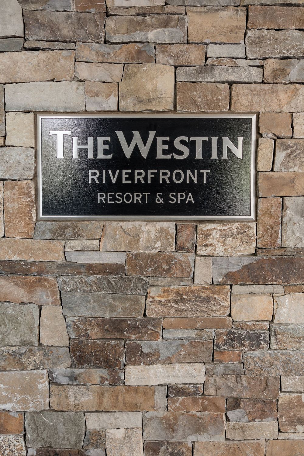 Stone wall with 'The Westin Riverfront Resort & Spa' signage mounted on rustic masonry.