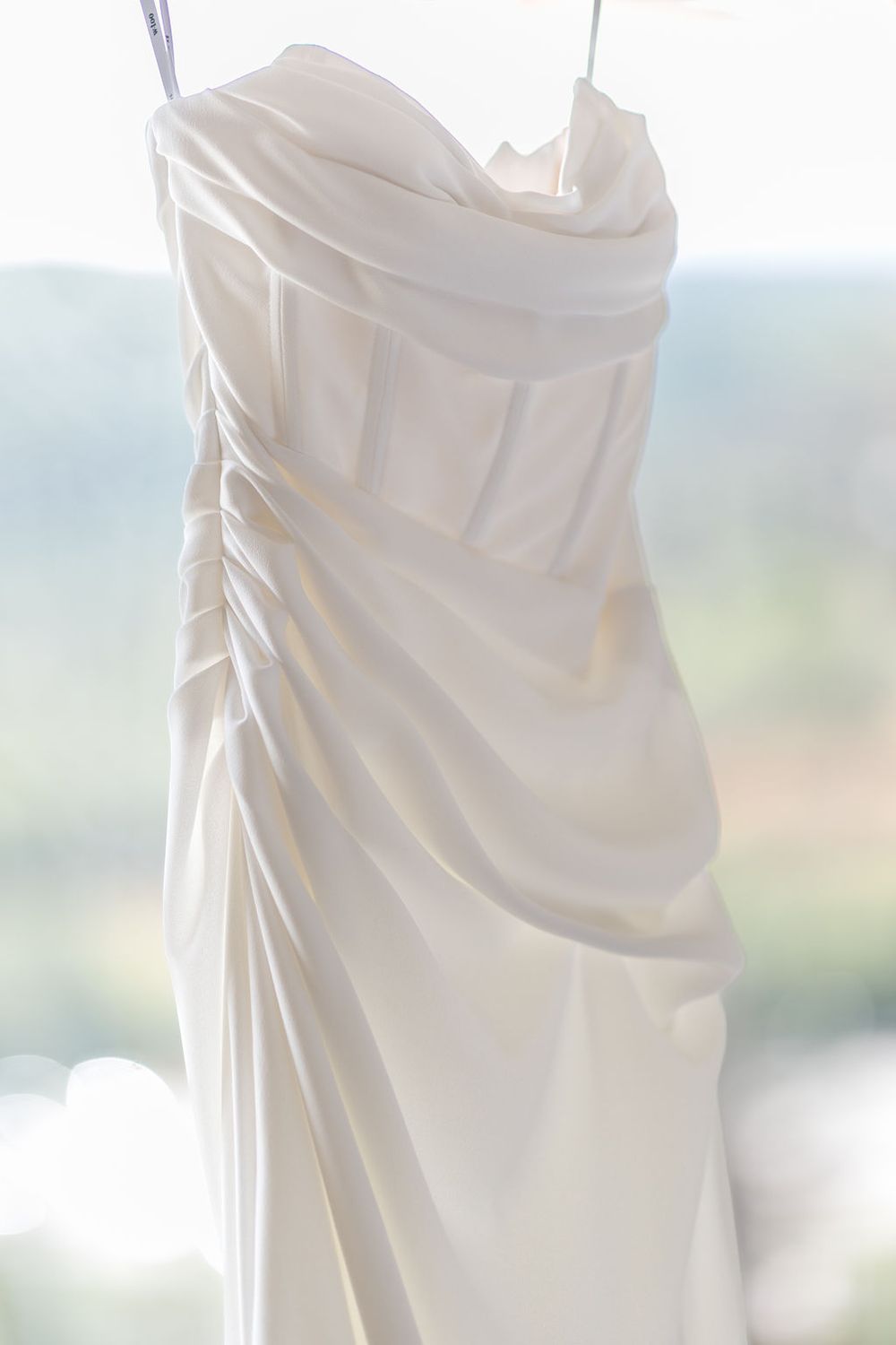 Close-up view of elegant white wedding dress fabric with delicate draping and ruching details.