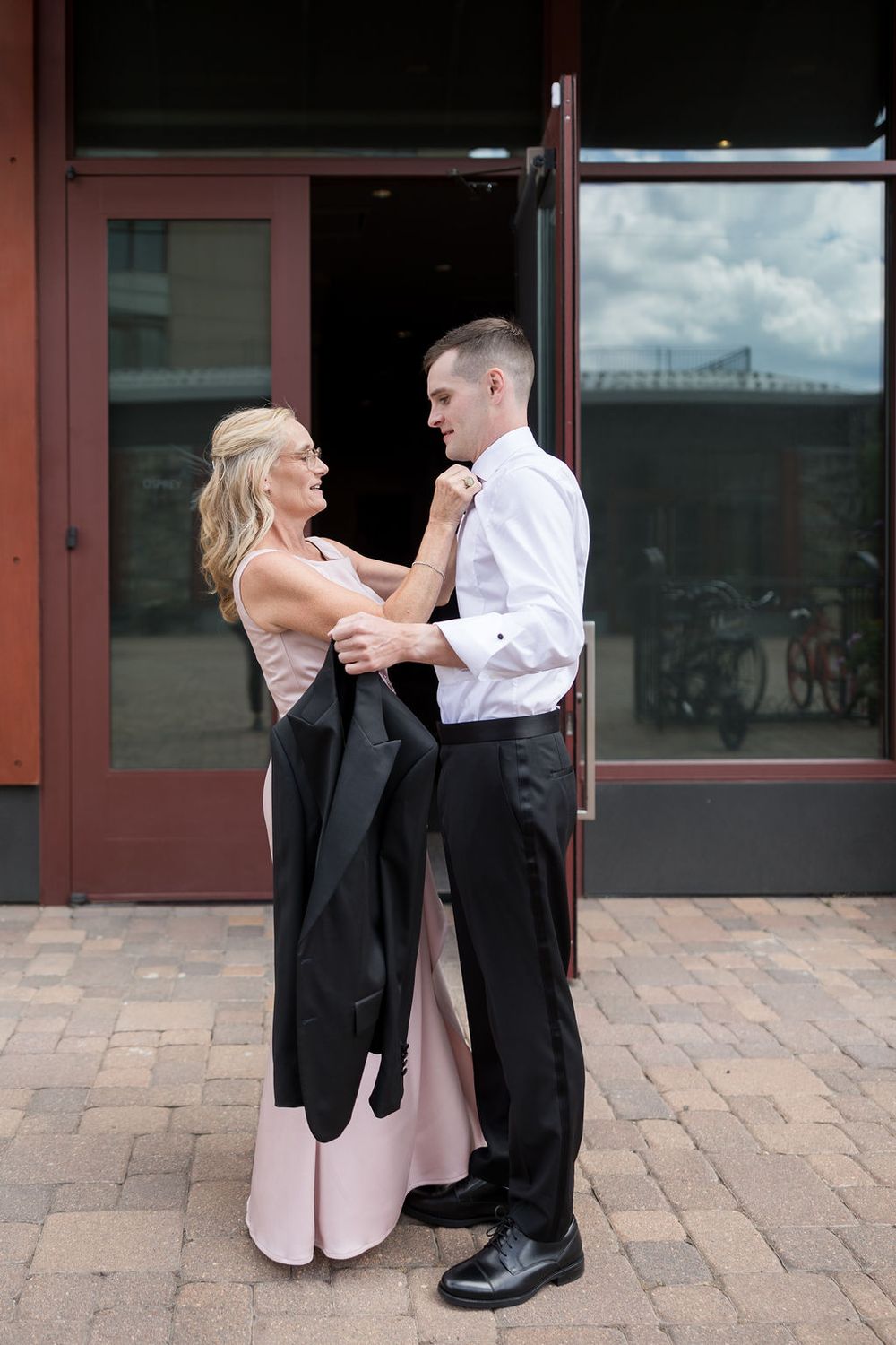 Couple in formal attire dancing on brick patio outside venue.