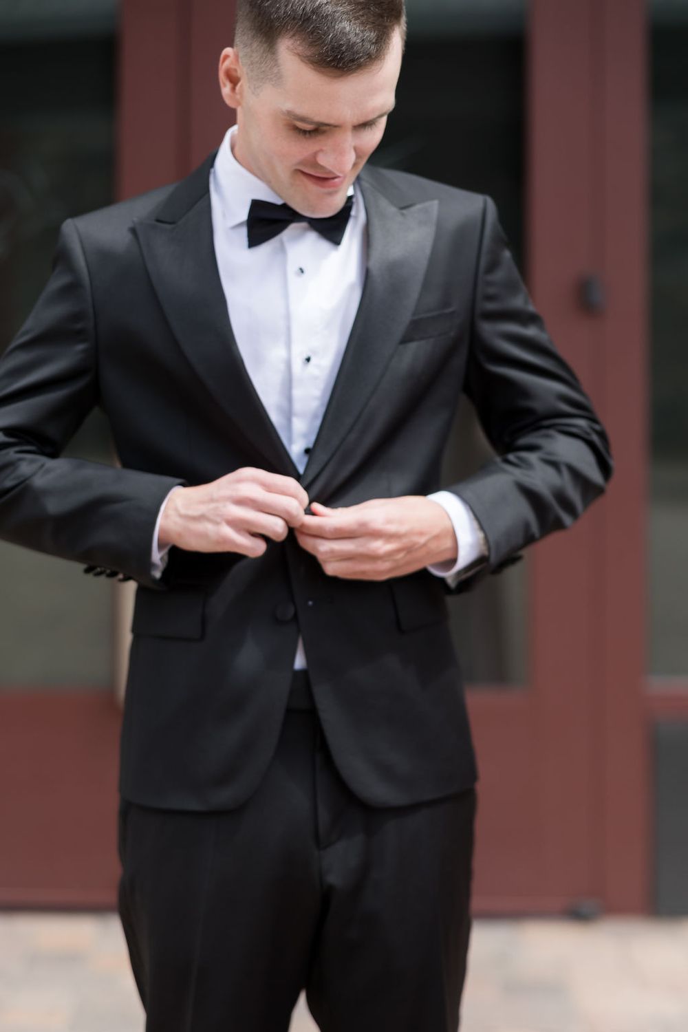Groom adjusts his bowtie and tuxedo in series of preparation shots.