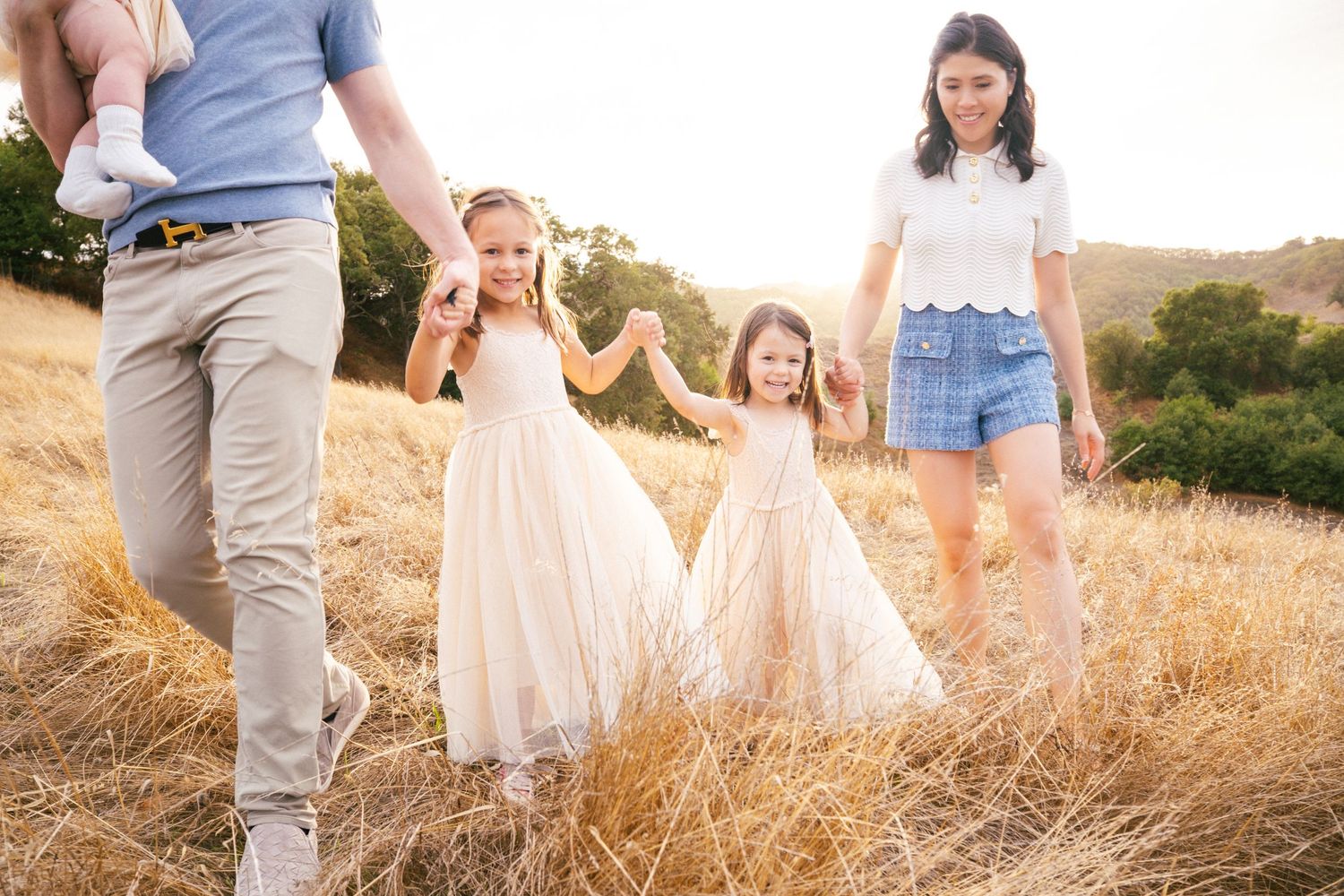 Young dancer in a flowing white dress twirls gracefully in a golden sunlit field during sunset.