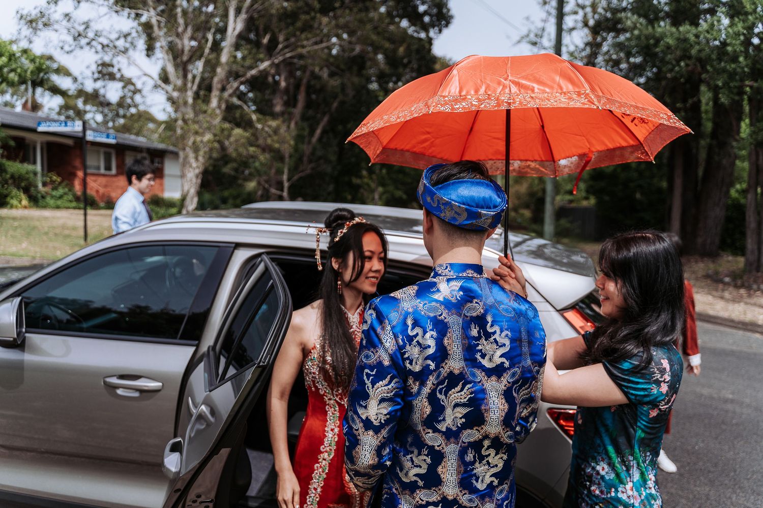 Wedding party with orange parasols walking together outdoors.