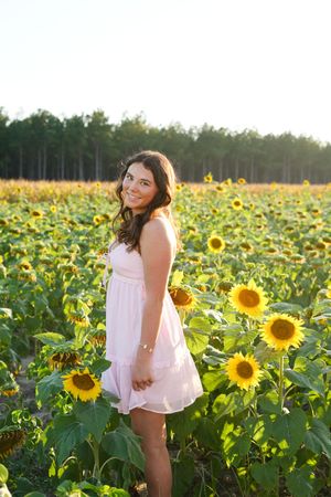 A dreamy summer photoshoot in a vibrant sunflower field at golden hour with light pink dress and natural backdrop.